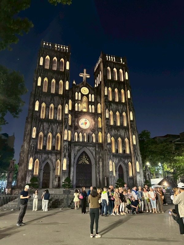 夜にライトアップされたハノイ大教会と、前に集まる観光客の様子